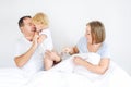 Happy and loving family morning concept. Cheerful parents in sleepwear having fun with their daughter on the bed. Family spending Royalty Free Stock Photo