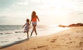 Happy loving family mother and daughter having fun on the beach at sunset - Mum playing with her kid next sea in holidays Royalty Free Stock Photo