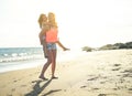 Happy loving family of mother and daughter having fun and playing on the beach - Young red hair mom carrying her kid on piggyback Royalty Free Stock Photo