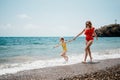 Happy loving family mother and daughter having fun together on the beach. Mum playing with her kid in holiday vacation Royalty Free Stock Photo