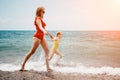 Happy loving family mother and daughter having fun together on the beach. Mum playing with her kid in holiday vacation Royalty Free Stock Photo