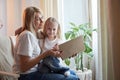 Happy loving family with mother and daughter reading book in living room. Woman mom and small child girl having Royalty Free Stock Photo