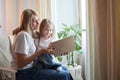 Happy loving family with mother and daughter reading book in living room. Woman mom and small child girl having Royalty Free Stock Photo