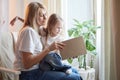 Happy loving family with mother and daughter reading book in living room. Woman mom and small child girl having Royalty Free Stock Photo