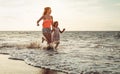 Happy loving family mother and daughter running on the beach at sunset - Mum having fun with her kid long sea shore Royalty Free Stock Photo