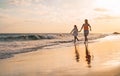 Happy loving family mother and daughter running on the beach at sunset - Mum having fun with her kid long sea shore Royalty Free Stock Photo