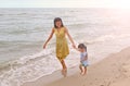 Happy loving family. Mother and her daughter child girl playing on beach background in the evening Royalty Free Stock Photo