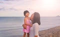 Happy loving family. Mother and her daughter child girl playing and hugging on sea background in the evening Royalty Free Stock Photo