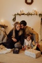 Happy loving family sitting on the floor with gifts and Christmas decoration in the background. Royalty Free Stock Photo