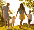 Happy loving family walking outdoor in the light of sunset. Father, mother, son and daughter. Royalty Free Stock Photo