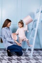 Happy loving family. young Mother in blue and her little daughter in pink clothes playing with pink gift box and blue ladder on Royalty Free Stock Photo