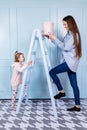 Happy loving family. young Mother in blue and her little daughter in pink clothes playing with pink gift box and blue ladder on Royalty Free Stock Photo