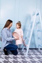 Happy loving family. young Mother in blue and her little daughter in pink clothes playing with pink gift box and blue ladder on Royalty Free Stock Photo