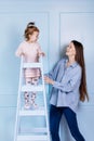 Happy loving family. young Mother in blue and her little daughter in pink clothes playing with pink gift box and blue ladder on Royalty Free Stock Photo