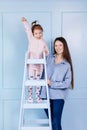 Happy loving family. young Mother in blue and her little daughter in pink clothes playing with pink gift box and Royalty Free Stock Photo