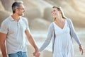 Happy and loving mature caucasian couple enjoying a romantic walk at the beach together on a sunny day. Cheerful Royalty Free Stock Photo