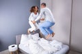 Couple Jumping Over Bed At Home Royalty Free Stock Photo