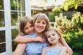 Happy loving middle-aged grandma hugging  granddaughters while standing in garden on summer day Royalty Free Stock Photo