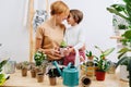Mother and daughter standing close, touching foreheads, holding pot with seedling