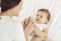 Happy, loving mother holding her baby's little feet while cuddling on bed together Royalty Free Stock Photo