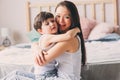 Happy loving mother hugs with child son in the morning in bed