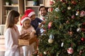 Happy loving parents decorating tree with small children. Royalty Free Stock Photo