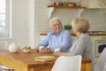 Happy senior couple sitting at kitchen table, drinking tea and enjoying quiet conversation Royalty Free Stock Photo