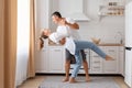 Happy loving young couple dancing on date in modern kitchen smiling husband and wife celebrating anniversary enjoying tender Royalty Free Stock Photo