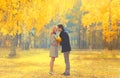 Happy loving young couple kissing and hugging in autumn park with yellow maple leaves on warm sunny day Royalty Free Stock Photo