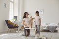 Happy mother and her daughter playing board game at home. Parent and child building tower from wooden blocks indoors Royalty Free Stock Photo