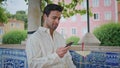 Happy macho calling smartphone waiting date at city park zoom on. Man talking Royalty Free Stock Photo