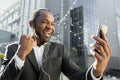 Happy male African American businessman standing outside office center wearing headphones and talking to his team Royalty Free Stock Photo