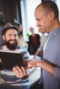 Happy male coworkers discussing over digital tablet