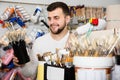 happy male customer examining various types of brushes in paint store Royalty Free Stock Photo