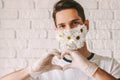 Happy male doctor in flower face mask gesturing heart symbol Royalty Free Stock Photo