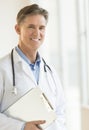 Happy Male Doctor Holding Clipboard In Clinic Royalty Free Stock Photo