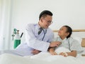 A happy male doctor uses a stethoscope to check the patient`s bo