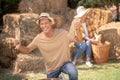 Happy male farmer showing cobs into the camera, female farmer shucking cobs behind him Royalty Free Stock Photo