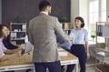 Happy male and female business people in the office shake hands to confirm their partnership. Royalty Free Stock Photo