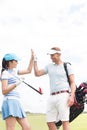 Happy male and female friends giving high-five at golf course