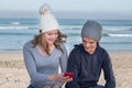 Happy male and female models wearing knitted beanies with Bluetooth speakers