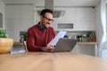 Happy male financial adviser reading income tax form and working over laptop on desk in home office Royalty Free Stock Photo