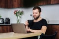 Happy male freelancer working at the dining table, drinking coffee