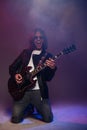 Happy male guitarist standing on knees and playing electric guitar Royalty Free Stock Photo