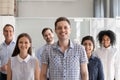 Happy male leader, coach posing with multiracial group of employ