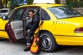 A smiling young man in car with opened door of yellow car, looking and smiling, with left leg outside, near guitar. Royalty Free Stock Photo