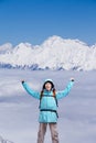 Happy male mountaineer man with raised arms. In background high mountains above clouds . Royalty Free Stock Photo