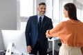 Happy male personnel manager and female job applicant shaking hands after successful employment interview in office