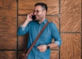 Happy male professional talking on smart phone standing against the wooden wall at the city Royalty Free Stock Photo