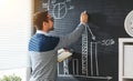 Happy male student, teacher, freelancer with chalk at blackboard